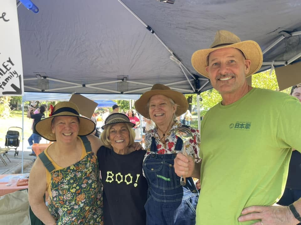 Four smiling neighbors working beneath a canopy