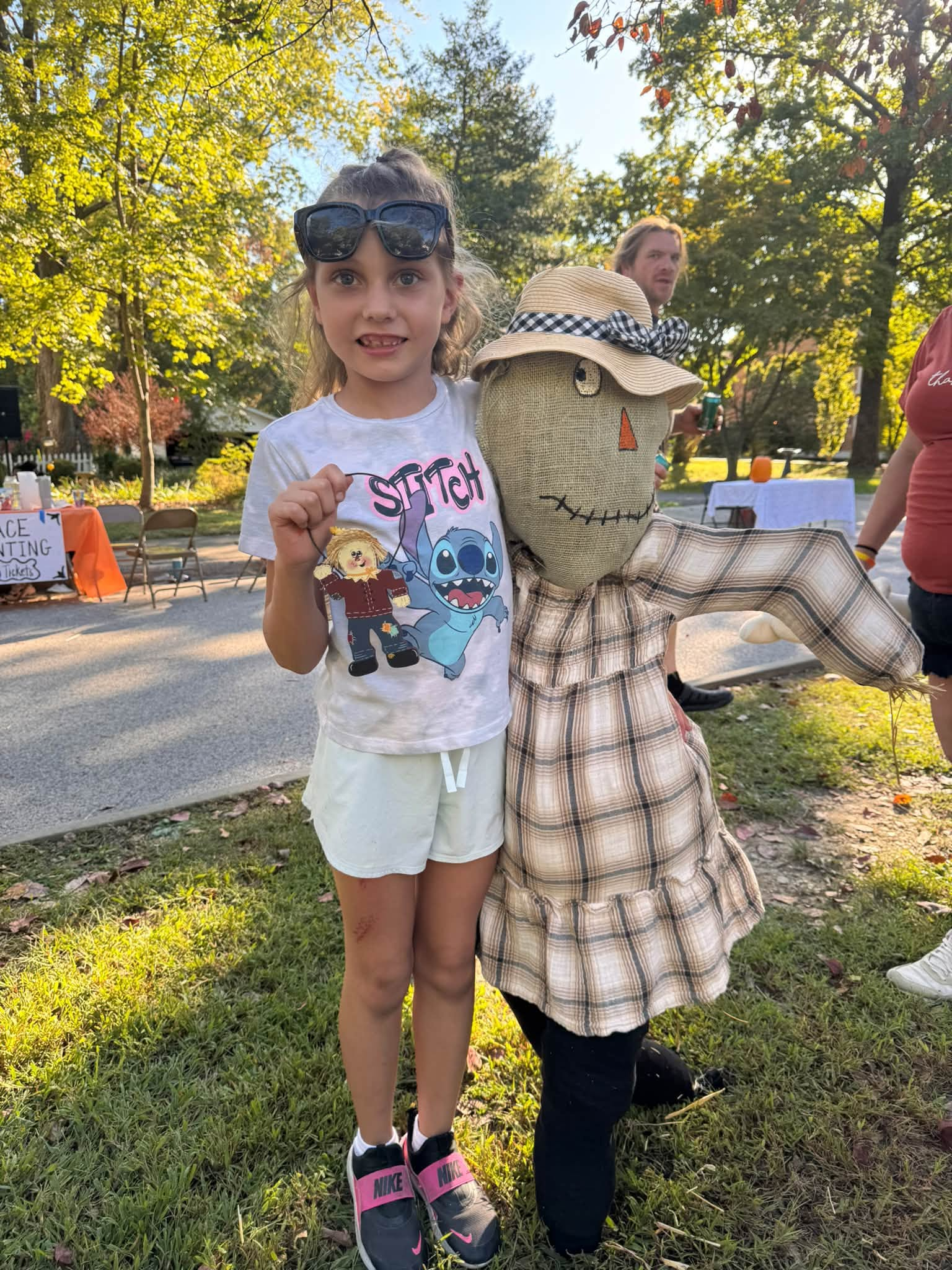 A girl standing beside a plaid scarecrow