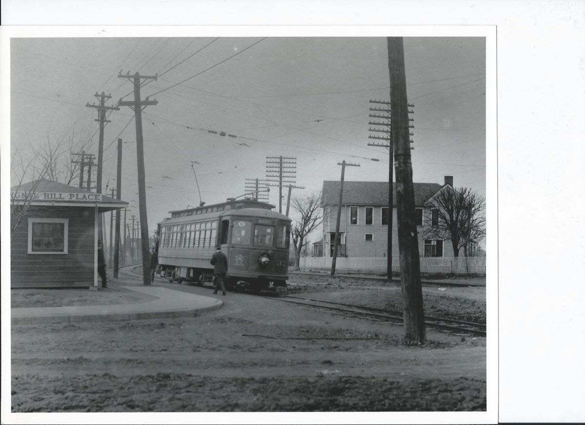 Trolley Car 32 stopped at Signal Hill Place with workers standing beside the track