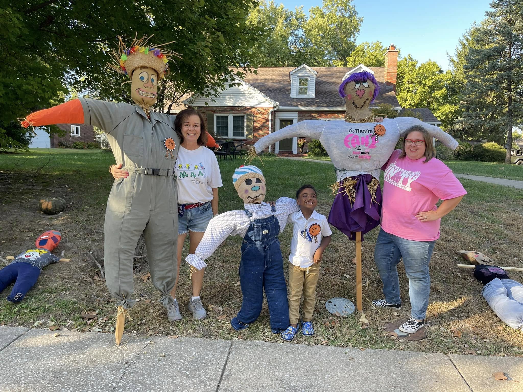 Neighbors pose with handmade scarecrows at the Harvest Hoedown